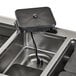 A black Vollrath drop-in hot food well on a black counter.