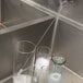 A Carlisle Sparta Coffee Urn Brush in a clear glass of water on a counter.