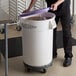 A person putting a purple lid on a large white ingredient storage bin.