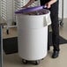 A person holding a purple lid over a large white container.