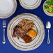 An Elite Global Solutions Doheny melamine plate with meat and vegetables on it.
