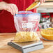 A person pouring macaroni into a Ziploc freezer bag.