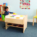 A child playing with a toy on a Whitney Brothers wood framed LED light table.