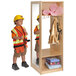 A boy wearing a hard hat and safety vest standing next to a Whitney Brothers dress up wardrobe with a mirror.