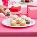 A hand holding a Diamond White oval platter with a cupcake on it.