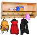 A Whitney Brothers wooden coat rack with backpacks and coats hanging on it.