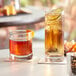 Two Acopa Bermuda rocks glasses filled with brown liquid and ice on a table with a lime slice.