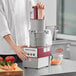 A chef using a Robot Coupe R2 DICE food processor to dice tomatoes.