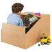 A child sitting in a Whitney Brothers wooden toy box reading a book.