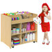 A little girl standing next to a Whitney Brothers wooden art supply storage cart holding a paint palette.