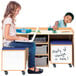 A girl sitting at a Whitney Brothers STEM activity desk using a laptop.