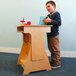 A young boy standing next to a Whitney Brothers standing children's desk.