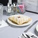 A Tuxton Monterey ivory china plate with a pastry with white frosting on it.