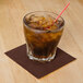 a straw in a glass with ice and brown liquid