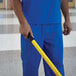 A man in blue scrubs holding a yellow telescopic pole.