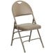 A beige metal folding chair with a padded tan seat.