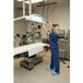 A person in medical scrubs uses a Rubbermaid HYGEN Quick-Connect Flexi-Wand with a green microfiber dusting sleeve to clean equipment in a hospital room.