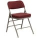 A burgundy Flash Furniture metal folding chair with padded fabric seat.