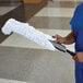 A man in scrubs using a Rubbermaid Flexi-Wand with a white microfiber sleeve to dust.