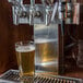 A glass of beer being poured using a Carlisle Sparta condiment dispenser brush.