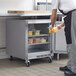 A man in a school kitchen using a Beverage-Air undercounter refrigerator to store food.