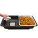 A hand pouring water into a Sterno SpeedHeat food warming tray on a table outdoors.