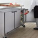 A man opening the doors of a Beverage-Air undercounter refrigerator on a counter in a professional kitchen.