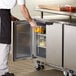 A person opening the door of a Beverage-Air undercounter refrigerator to get food.