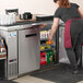 A woman in a red apron opening an Avantco back bar refrigerator.