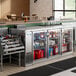 An Avantco stainless steel back bar refrigerator on a counter with drinks inside.