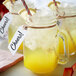 A close-up of a Monin glass jar of yellow liquid with a straw and a label.