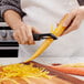 A person using an OXO vegetable peeler to peel a carrot.