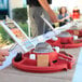 A person using a Sterno Family Fun S'mores Maker to roast a marshmallow over a table with s'mores on it.