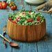 A Fox Run acacia wood salad bowl filled with salad on a table.