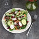 A plate of salad with radishes, cucumbers, and carrots with a fork on the side.