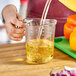A person pouring purple liquid into a purple measuring cup.