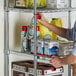 A man sliding a box of cleaning supplies onto a Regency chrome wire shelf.