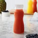 A clear polycarbonate bottle of orange juice on a white counter.