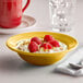 A Tuxton saffron grapefruit bowl filled with yogurt, raspberries, and nuts.