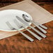 A white plate with a Walco Vestige stainless steel demitasse spoon and fork.