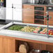 A Delfield drop-in refrigerated cold food well holding four pans on a counter in a salad bar.
