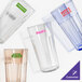 A group of empty Cambro clear plastic tumblers with customized labels on a table.