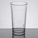 A clear Carlisle plastic tumbler with a black rim on a table.