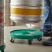 A man using a Regency keg dolly with green wheels to transport a keg.