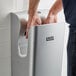 A man using a Lavex Silver high speed vertical hand dryer to dry his hands.