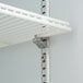 A white metal shelf with a metal rod attached to it.