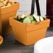 A group of orange Tablecraft square condiment bowls with cucumbers and crackers on a counter.