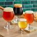 A group of Acopa Belgian Beer Tasting glasses filled with different types of beer on a table in a brewery tasting room.