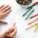 A child's hand holding a red Choice School Crayon drawing on paper.