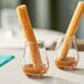 Acopa tulip glasses filled with churros and caramel sauce on a table.